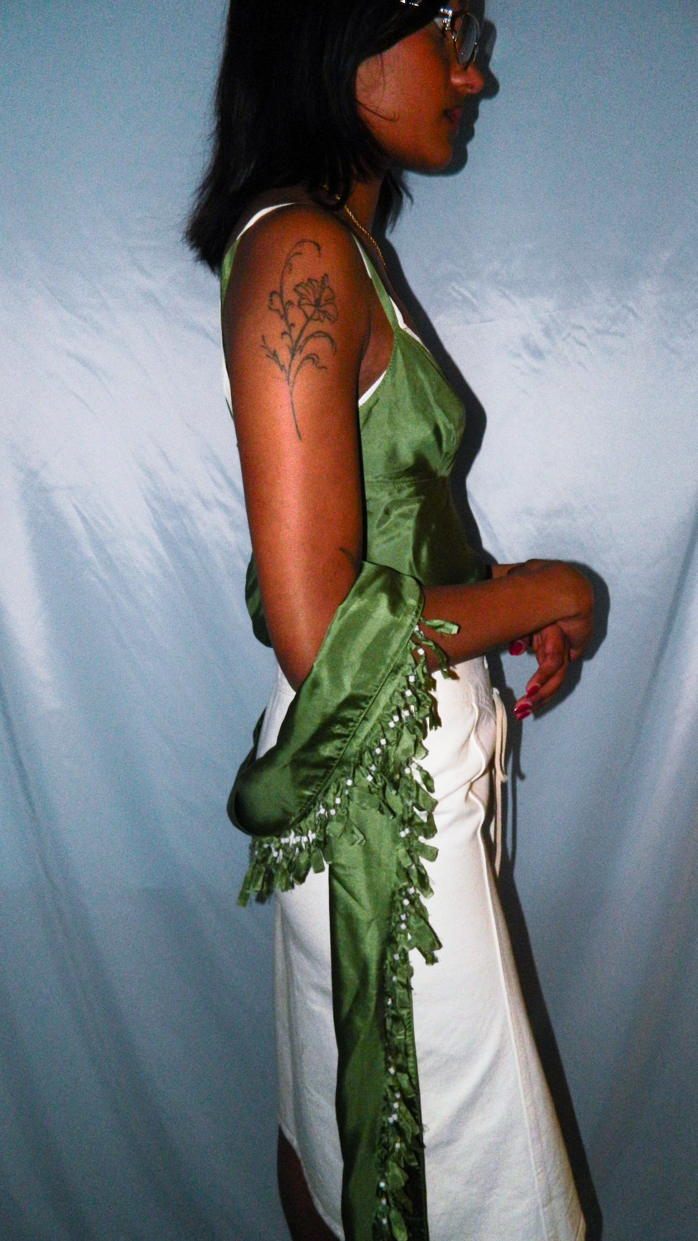 Person wearing a green top and white pants with a blue curtain background